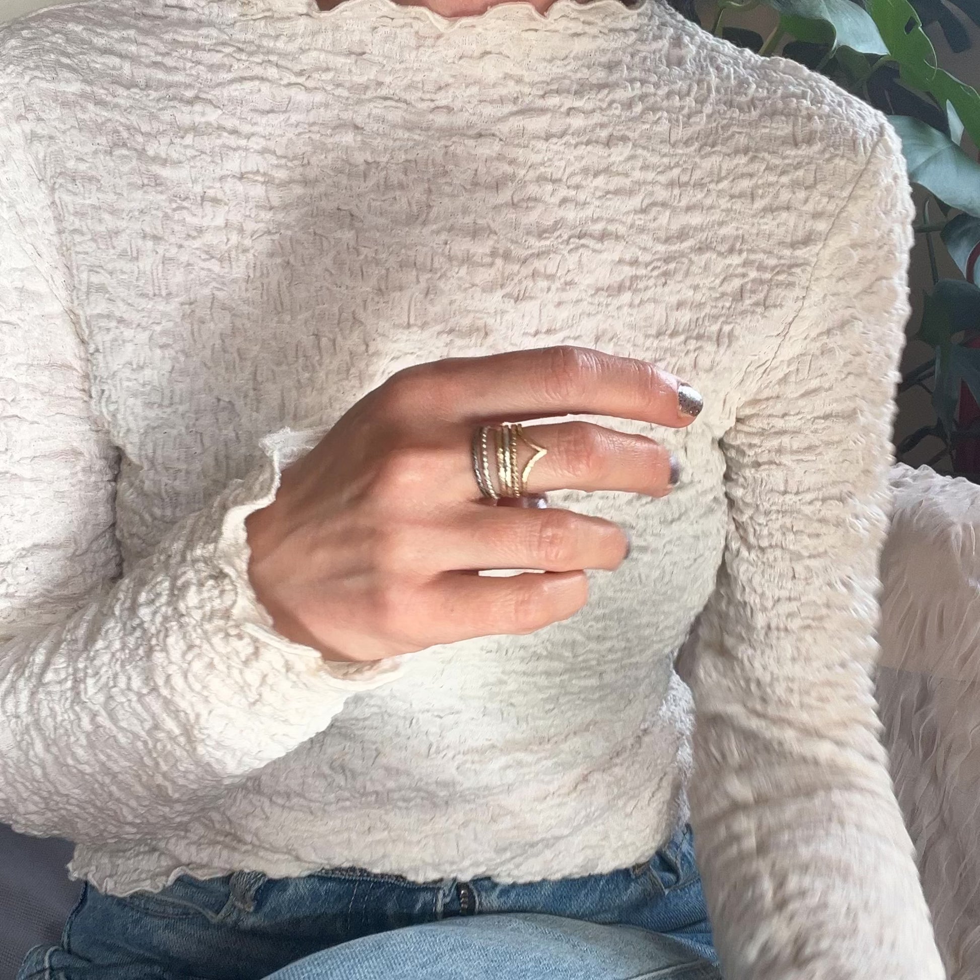 a woman with a stack of gold and silver rings on her  middle finger reaching for a cup of coffee